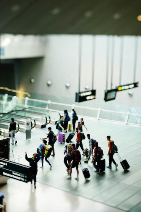Travelers walk through an airport — sustainable travel
